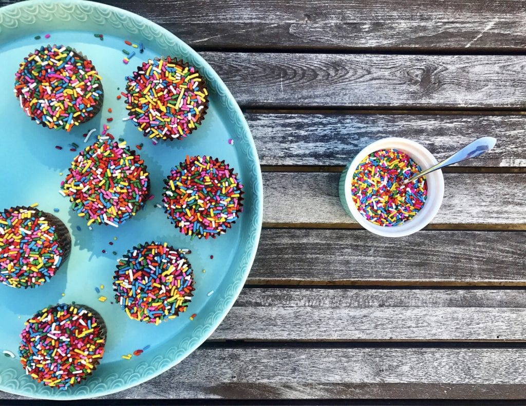 tray of grain free chocolate birthday cupcakes with rainbow sprinkles