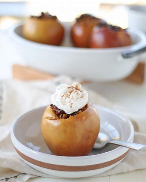 apples stuffed with date and walnut filling topped with whipped cream and cinnamon