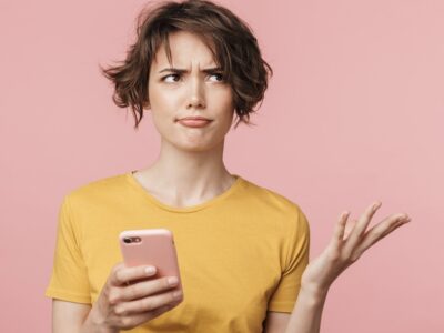 Woman looking at her phone, unsure which wellness rule actually applies to her
